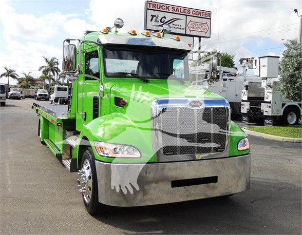 Green Peterbilt tow truck front view with chrome grille and bumper, stock photo at a truck center.