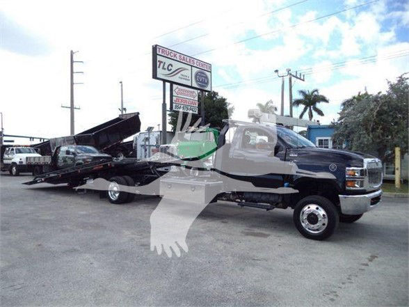 Tow truck with a black flatbed attached, International CV model in a dealership lot.