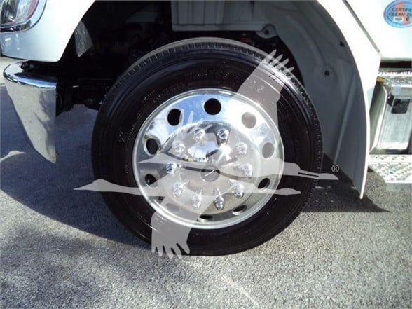 Freightliner M2 106 Plus front wheel and chrome hubcap with lug nuts visible under wheel well.