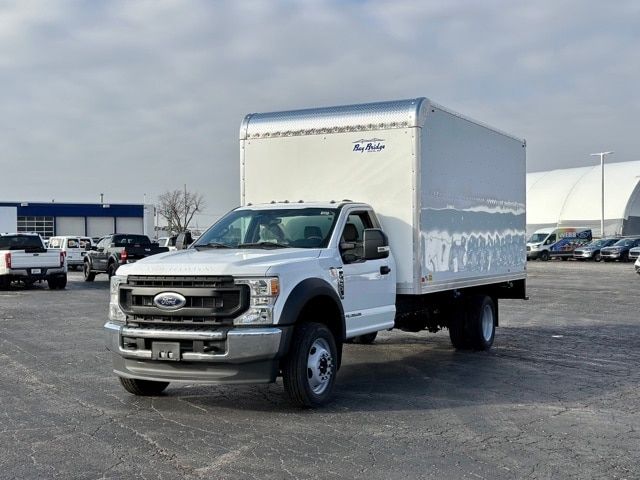 Ford F-550 regular cab medium-duty box truck with a white cab and a large white cargo box, parked in an open lot.