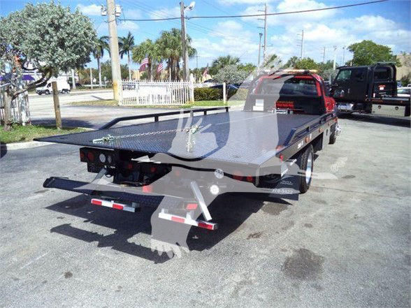 Ram 5500 flatbed tow truck rear view with open aluminum diamond plate bed and dual rear fenders.