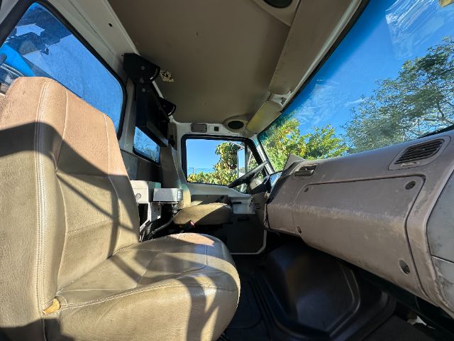 Interior of a 2005 Sterling L7500 vacuum truck cab showing brown cloth seats, steering wheel, dashboard, and driver-side door. Clear daytime light.