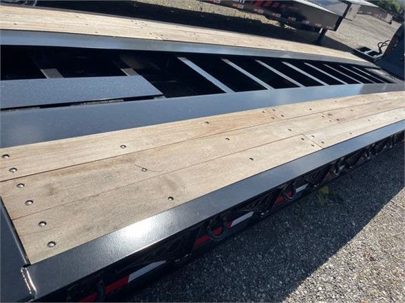 Flatbed trailer with wooden deck planks and metal frame. Visible text on deck edges and frame. 26 ft deck area with reinforcement beams.