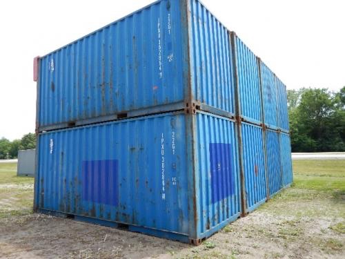 Two blue 20-foot shipping containers stacked, showing corrugated metal with white markings and faded numbers along the side.