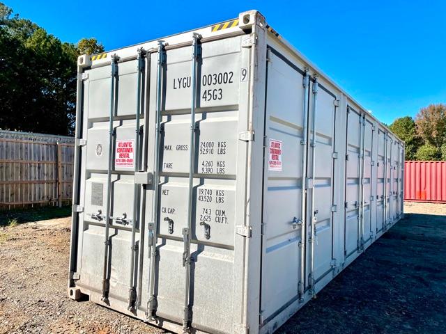 Trailer container showing rear doors with black vertical bar latches and measurements printed on door; identification text LYGU 003002 9G; small warning labels on doors; exterior silver metal with yellow/black corner protectors.
