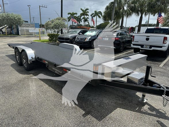 Flatbed trailer in parking lot showing dual-axle metal deck with diamond plate on front toolbox, hitch, and safety chains. Visible text includes '55KF1AJ27P1000733' on the VIN tag and 'FZTR00733' on stock label.
