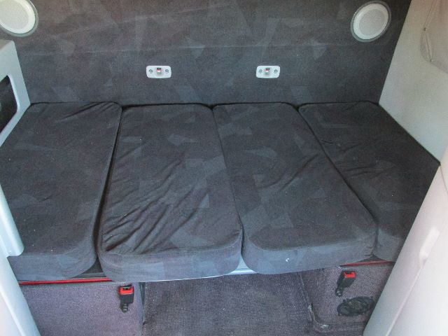 Interior sleeper bunk cushions folded into a bed area in a Volvo 780 truck sleeper with dark upholstery and side panels.