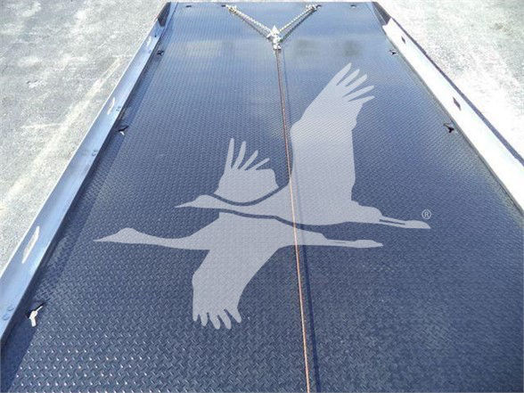 Aluminum flatbed truck, deck with large white bird logo, black diamond plate surface, parallel center seam lines.