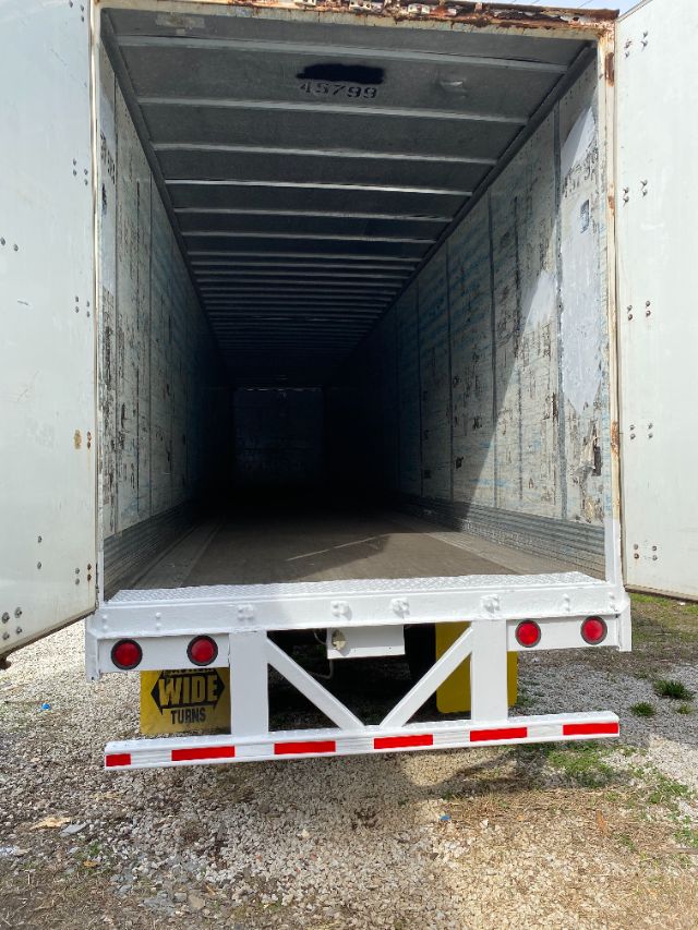 Trailer open at rear showing long interior cargo space with Duraplate walls, rear lights, and wide-turn sticker on bumper.
