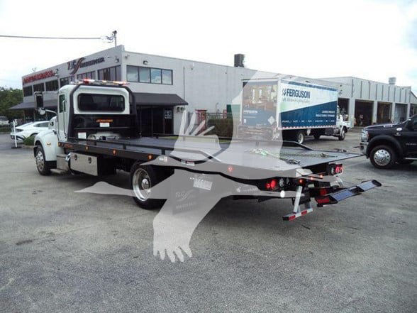 Peterbilt 337 tow truck with flatbed, rear view showing loading ramps and extended bed.