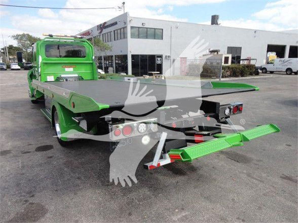 Green tow truck with flatbed in a dealership lot, MV607STEPSIDEFM stock number, International MV model.
