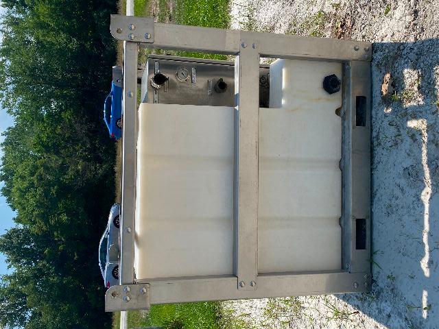 Trucking equipment chemical tank mounted in steel frame with control panel and diffusers. Large white plastic tank inside metal rack.