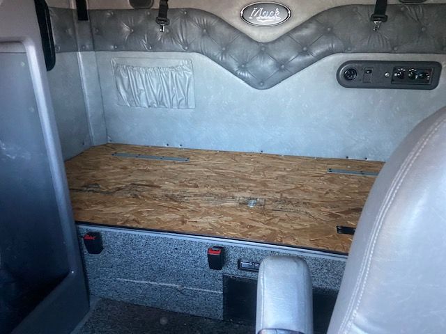 Truck sleeper cabin interior with wood cargo platform and quilted gray headliner visible.