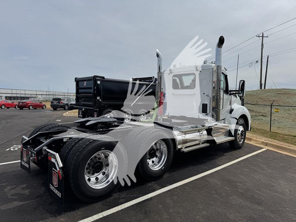 Kenworth T880 cab and chassis truck in a parking lot, side view showing dual rear axles, chrome fuel tanks, and rear frame.
