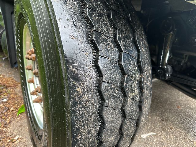 Close-up of a truck tire tread with mud on the road surface and wheel hub visible.