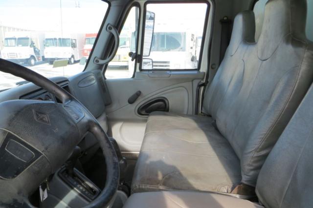 2003 International 4300 cab interior showing steering wheel and front bench seat with light gray upholstery.