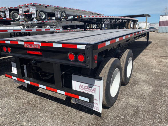 Flatbed trailer with dual rear axles and ILOCA mudflaps showing Fontaine brand signage and red/white reflective tape.
