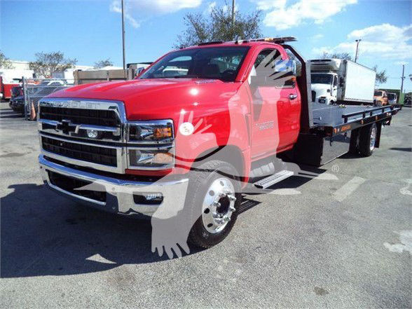 Chevrolet Silverado 6500HD tow truck with red cab and flatbed, front grille and bumper visible.