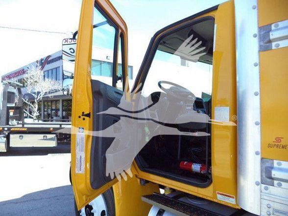 Truck cab entry showing open door of a yellow 2019 International DURASTAR 4300 with interior seats and dashboard visible.