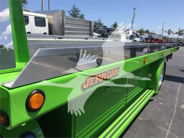 Peterbilt 337 tow truck with bright green body and silver deck panels, JERRODAN branding on side and chrome accents.