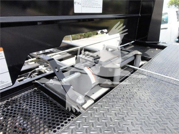 Isuzu NRR truck bed area showing hydraulic lift or towing equipment with metal rollers and perforated platform.
