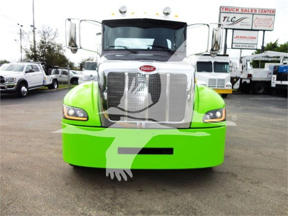 Front view of a bright green Peterbilt 337 truck with chrome grille and headlights.