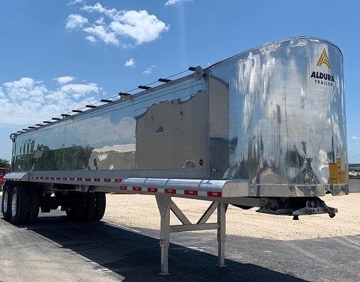 Aluminum end dump trailer 39ft with Aldura Trailers branding, polished chrome finish, tandem axles, landing gear visible.
