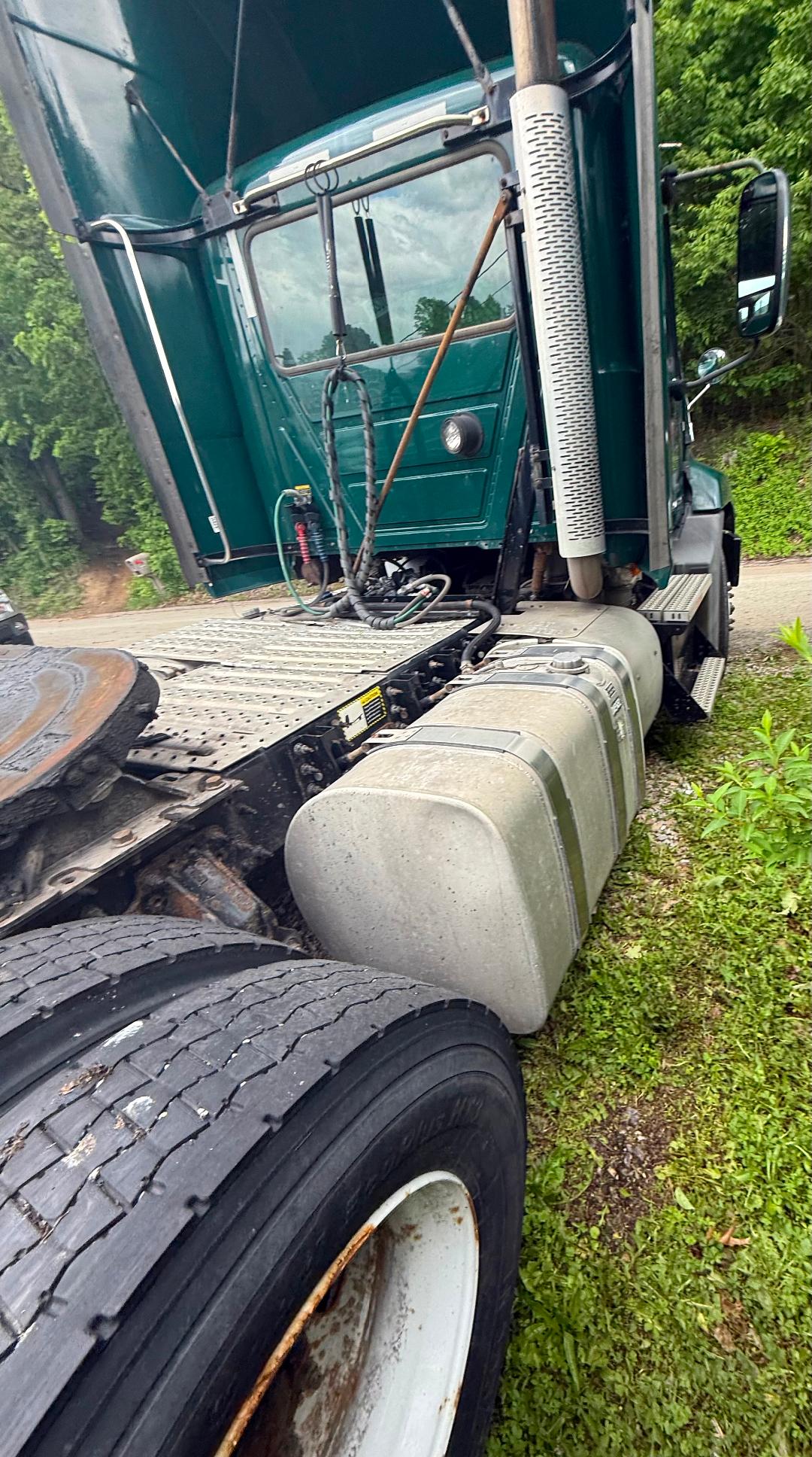Truck cab area with fuel tanks and dual rear tires; green Mack CXU 612 truck with vertical exhaust, side steps, and fuel tanks visible.