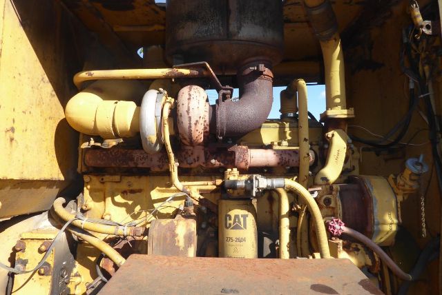 Caterpillar engine bay of a 1979 16G grader showing turbocharger, hoses, hydraulic lines, and a CAT oil filter.