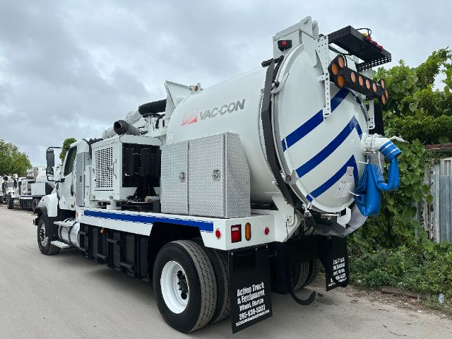 Vacuum truck with circular rear tank labeled VACON on a 2014 Freightliner 114SD, side view showing rear chassis, hose reel, and loading area.