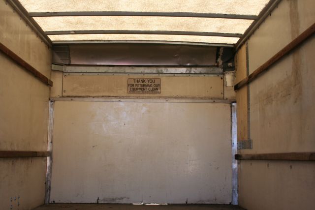 Truck box interior showing side walls and a rear door with a small sign reading 'THANK YOU FOR RETURNING OUR EQUIPMENT CLEAN'