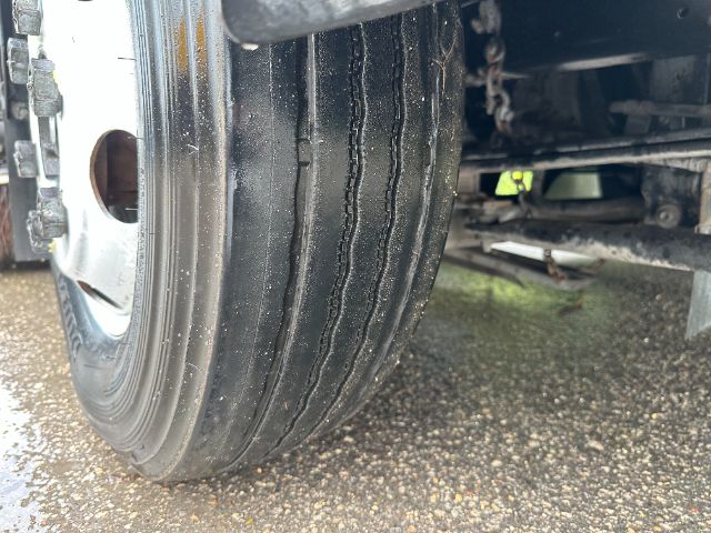 Isuzu NPR-HD sweeper truck front wheel and tire in view showing tread grooves and undercarriage.