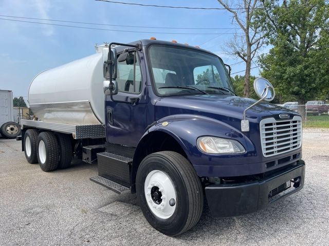 Vehicle side view of a 2013 Freightliner M2 septic truck with a large cylindrical tank mounted on the chassis, dark blue cab, chrome grille, and dual rear wheels.