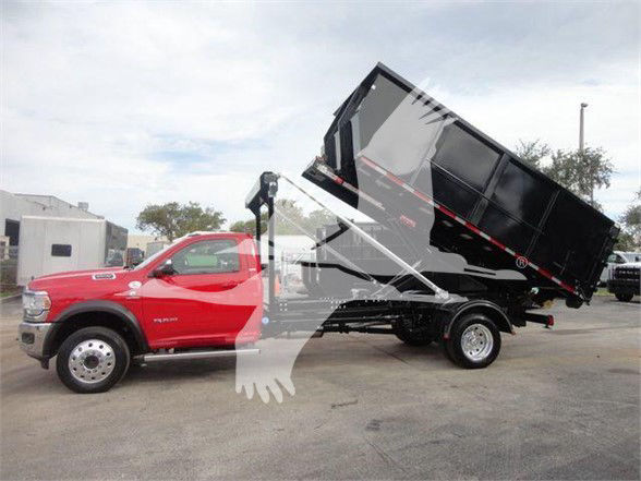 Ram 5500 SLT hooklift truck with a raised black dump bed on the back. Red cab with towing mirrors. Visible text on the truck: none clearly legible; some faint stickers on the side of the dump bed. Stock number and category are provided in t