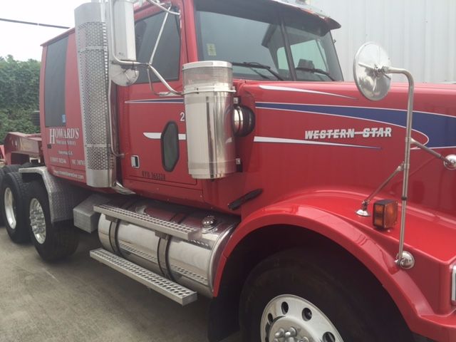 Truck side view showing red Western Star 4900fa with chrome fuel tanks, step bars, and badge reading 'HOWARD'S' on door. 'WESTERN-STAR' logo on front fender.