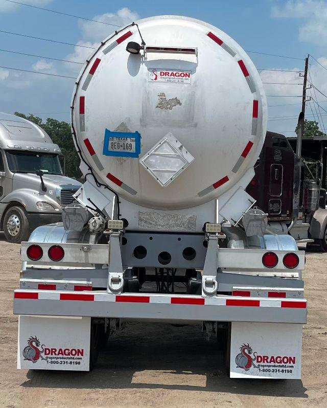 Crude oil tanker trailer rear showing circular aluminum DOT407 tank with red reflective strips, back bumper steps, taillights, and Dragon branding.