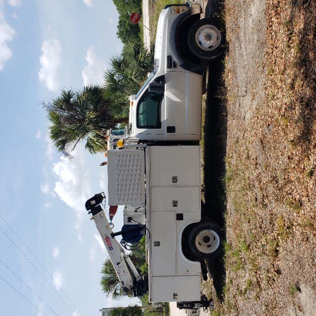 White Ford F-550 utility truck with bucket lift and storage compartments visible side view.