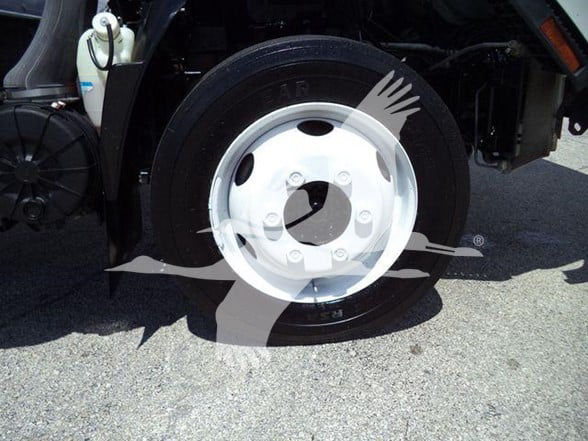 Isuzu NPR HD truck wheel and front tire with white hubcap and surrounding components visible.