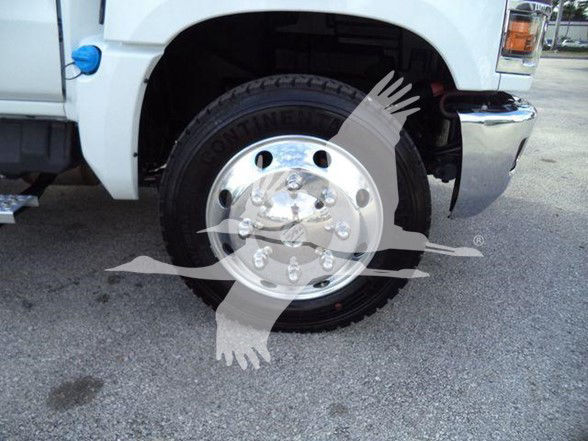 Front wheel and tire area of a 2023 Chevrolet Silverado 6500HD with chrome hubcap, partial front bumper, and wheel well showing tire treads.