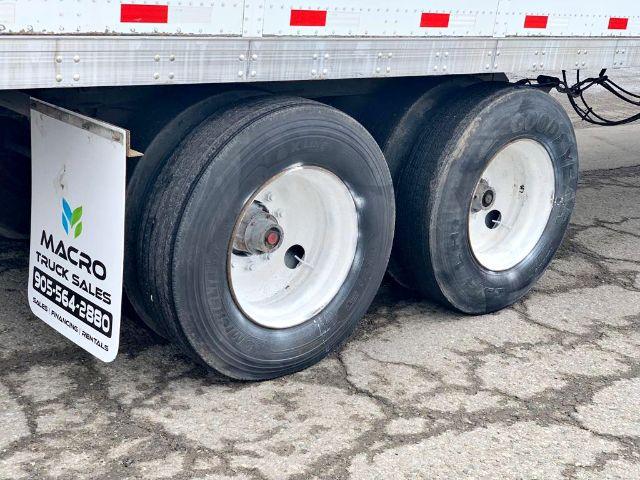 Trailer tires and axle of a 2009 Stoughton dry van trailer; side panel shows MACRO Truck Sales sign with contact number.