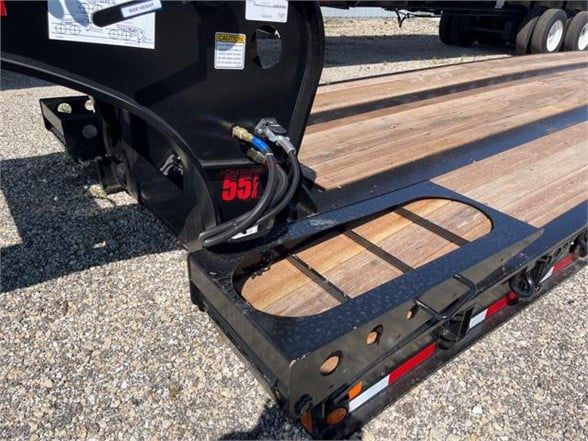 Lowboy trailer with wooden deck and hydraulic connection; 55-ton capacity Fontaine paver lowboy, black frame, visible piping and metal ramp/step.
