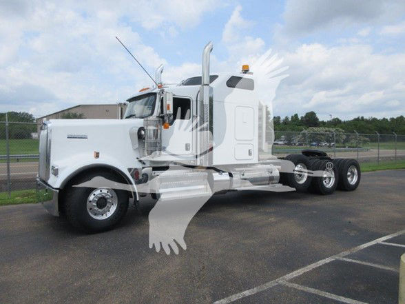 Kenworth W900L conventional sleeper truck in a parking lot, side view showing chrome fuel tanks, dual rear axles, and a white exterior.