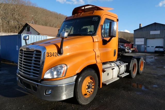 Orange Freightliner Cascadia 125 daycab truck front-left side view with front grille, headlights, and fuel tanks visible.