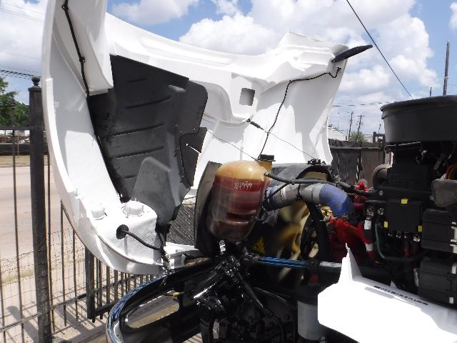Truck engine bay of a 2018 International 4300 with hood open, showing coolant reservoir, engine components, and front cab area.