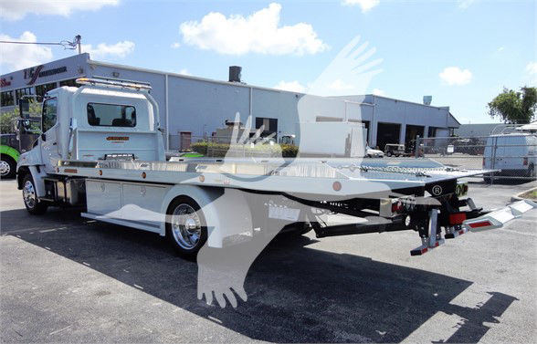 Flatbed tow truck with white cab and long aluminum bed, rear view showing towing equipment and winch, stock number J51795.