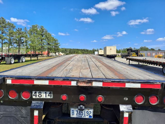 Flatbed trailer rear with license plate and stock number 4814, long wooden deck, red and white reflectors, blue sky, Fontaine used trailer.