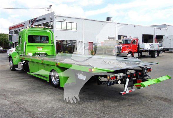 2022 Peterbilt 337 tow truck with bright green flatbed and rear winch area, seen from rear three-quarter view in a dealership lot.
