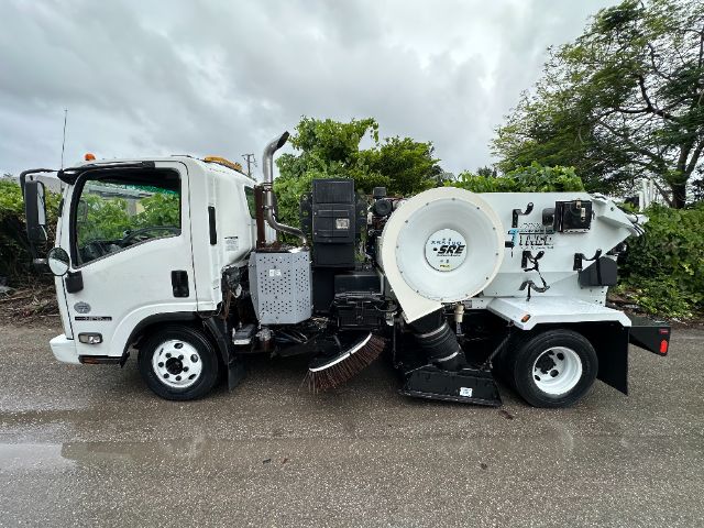 Isuzu NPR-HD street sweeper truck side view showing front cab, large vacuum/sweeper components, hoses, and rear sweeping mechanism.