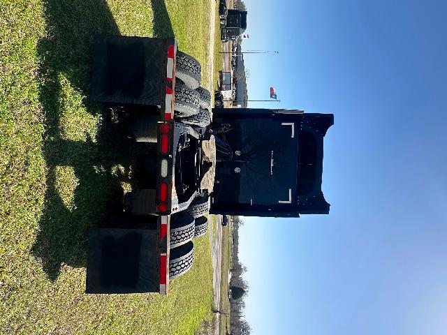 Peterbilt 579 in-service used truck. Rear view showing chassis and dual rear axles, black dump/box bed, rear lights, and mud flaps.