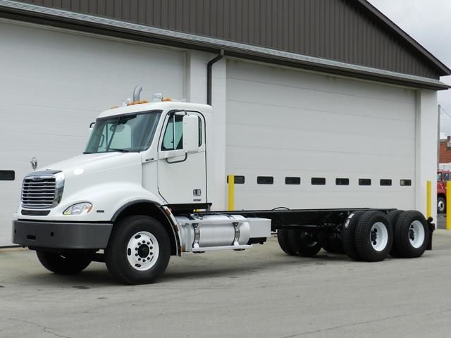 Freightliner cab and chassis truck in front of a building showing wheels, cab, and chassis with dual rear axle.